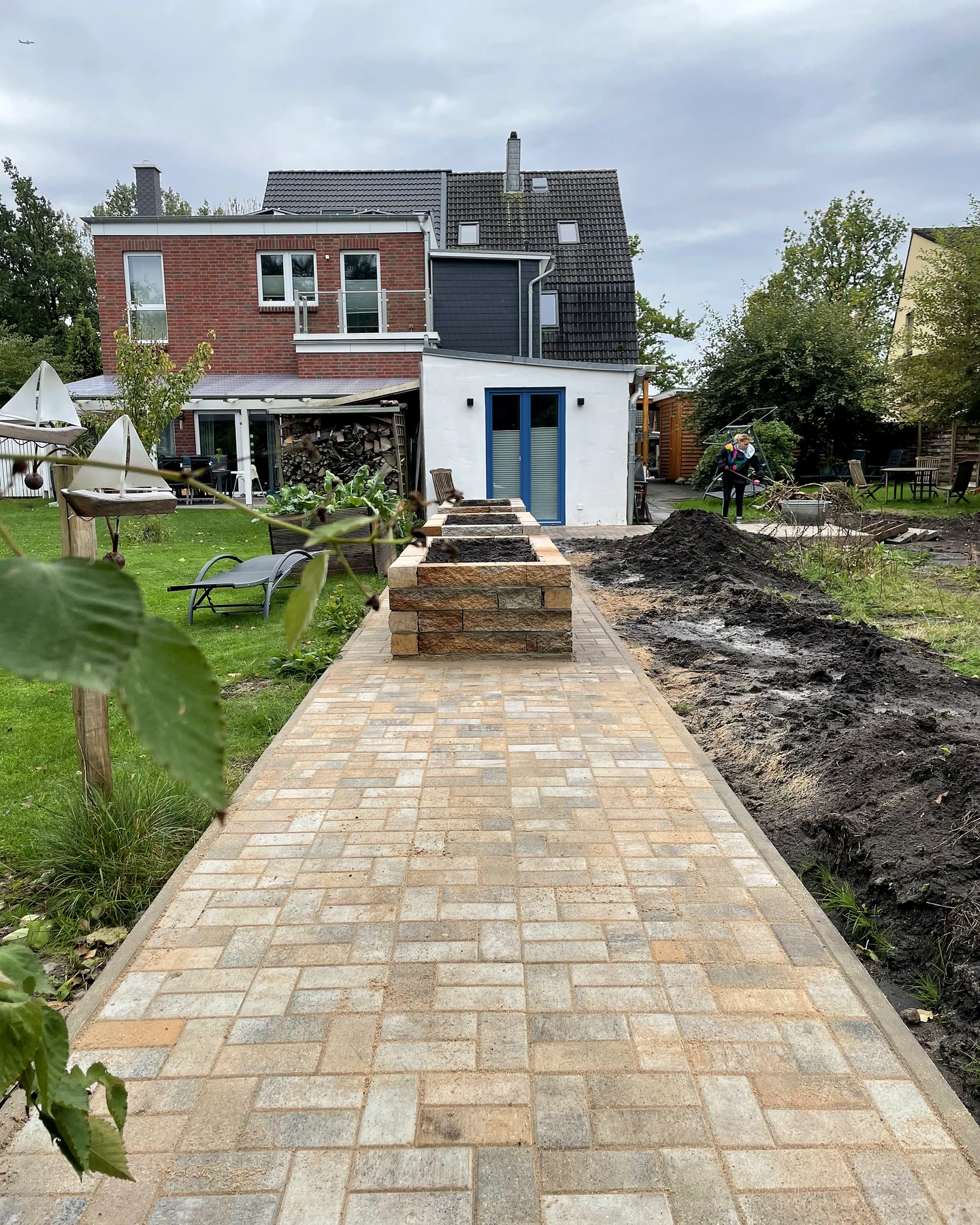 Neu angelegter Pflasterweg durch eine große Gartenanlage